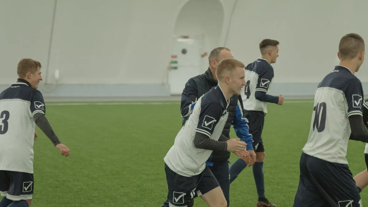 Young soccer players training with their coach on an indoor turf field inside a sports dome