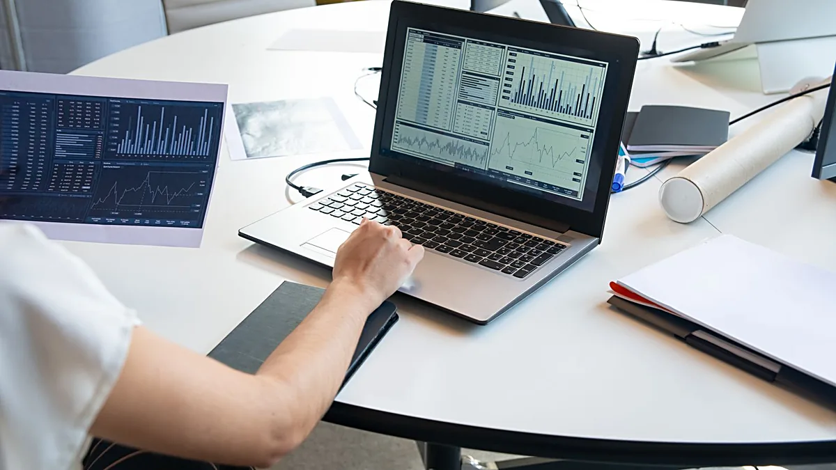 Business person evaluating analytics charts and graphs on a laptop in a modern office