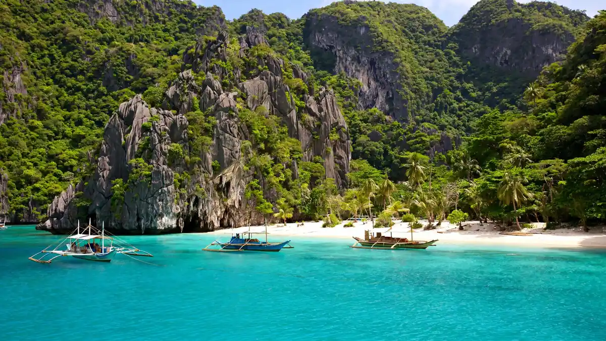 Bangka outrigger boats on a turquoise lagoon in El Nido, Palawan, with limestone karsts — best places in the Philippines to visit