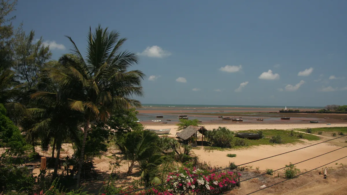 Malindi harbour in Kenya with fishing boats and the white Vasco da Gama Pillar cross visible on the headland across the bay