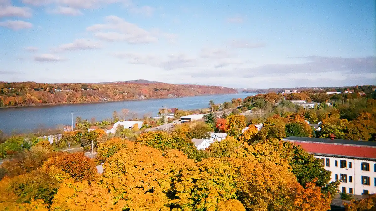 Hudson River winding through the Hudson Valley in fall, with golden and orange foliage on the hillsides — best places to visit in the Hudson Valley