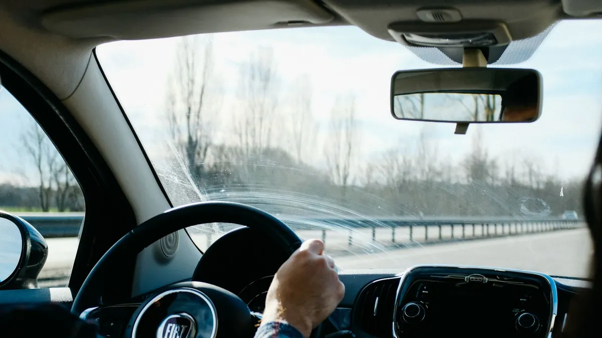 Driver and passenger sharing a car journey on a highway, seen from inside the vehicle