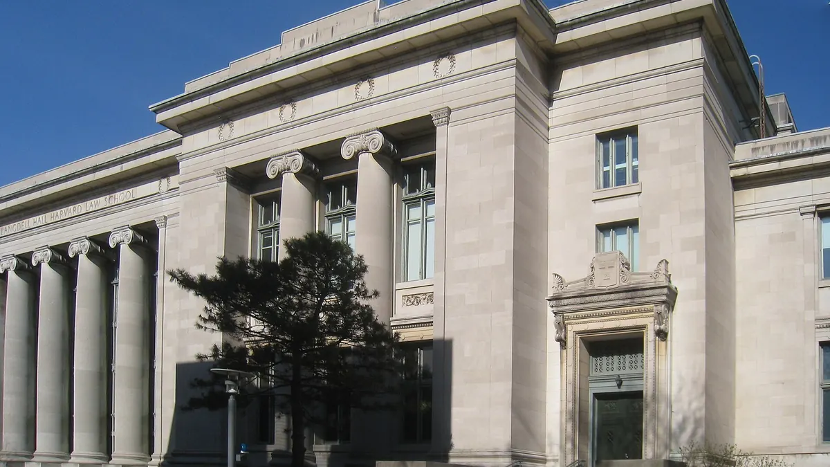 Langdell Hall at Harvard Law School, a stone law school building with tall columns under a clear blue sky