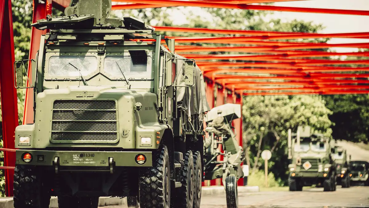 U.S. Marine Corps 7-ton trucks towing howitzers in a supply convoy on a road in Palawan, Philippines, illustrating military logistics and frontline supply runs