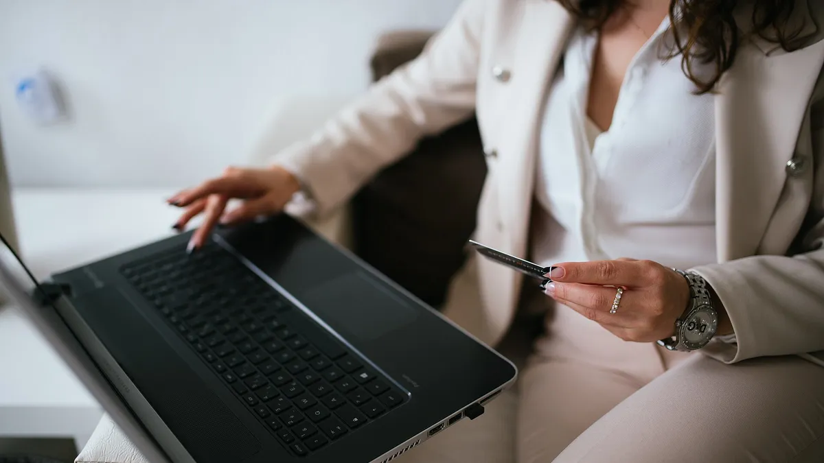 Business professional shopping online from a home workspace with a laptop and credit card, representing the global impact of digital marketing on consumer products and services