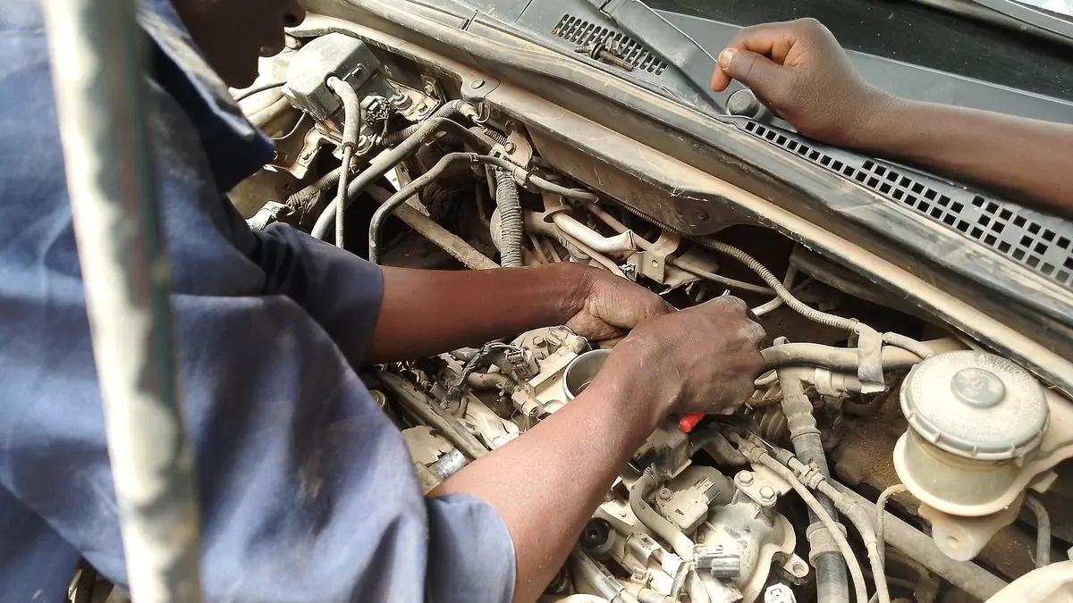 Mechanic repairing a car engine in an auto workshop during a full-service vehicle inspection