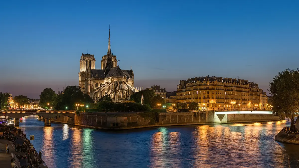 Notre-Dame Cathedral and Île de la Cité at dusk across the Seine in Paris, with historic bridges and golden evening light
