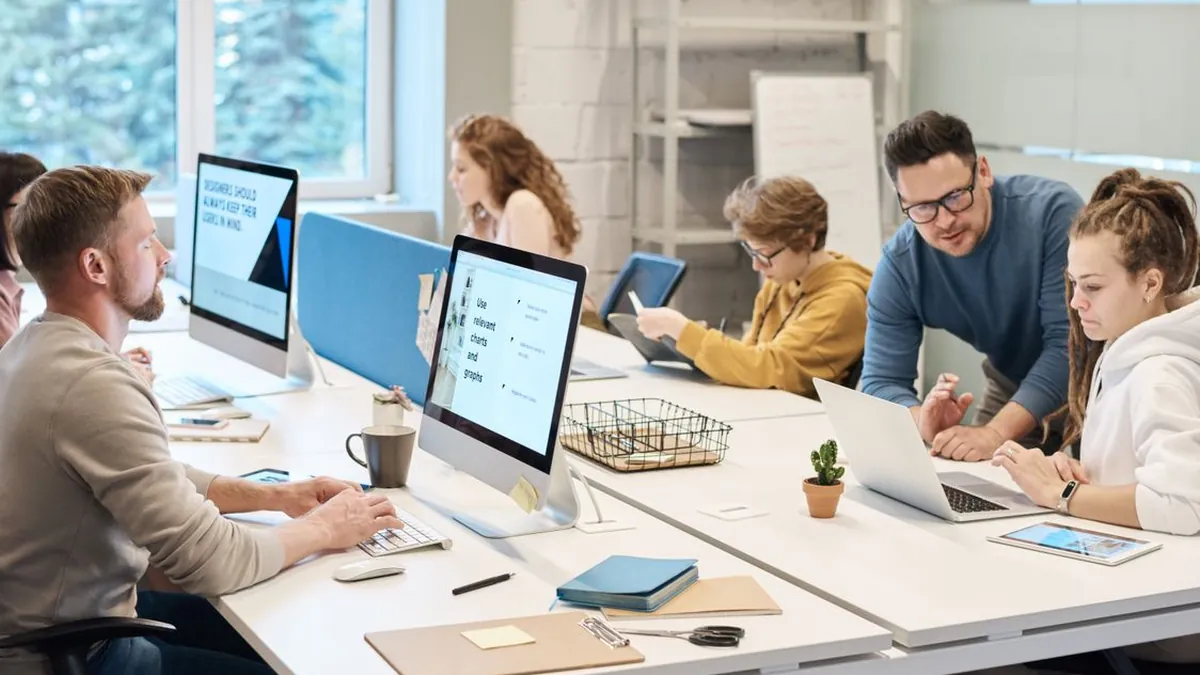 Team of professionals working together at computers in a modern office, collaborating on business technology