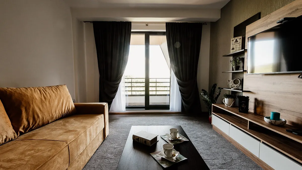 Elegant living room with a wall-mounted TV above a low media console with closed storage, styled shelves and a comfortable sofa