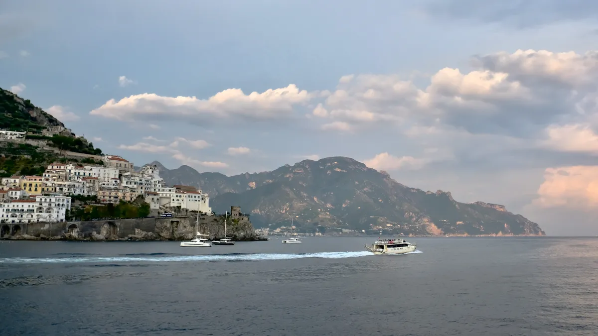 Positano on the Amalfi Coast at dusk, with pastel cliffside houses and warm evening lights above the sea