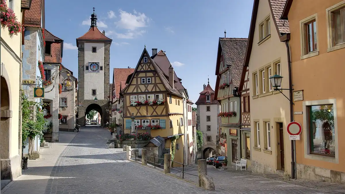 The Plönlein corner in Rothenburg ob der Tauber, with its leaning yellow half-timbered house, fountain, Siebers Tower and Kobolzell Gate