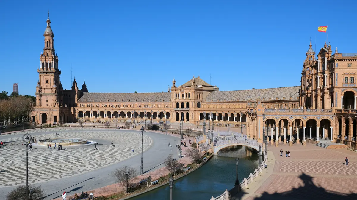 Plaza de España in Seville with its canal, tiled bridges and grand semicircular building under a blue sky