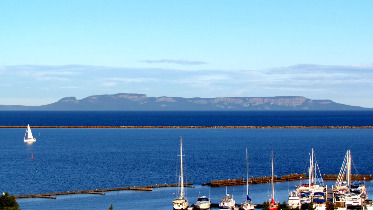 Sleeping Giant formation across Lake Superior from the Thunder Bay marina, with sailboats on the harbour under a clear blue sky