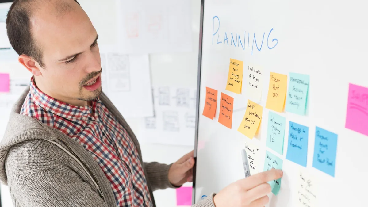A team leader running a planning session with colleagues around colourful sticky notes, aligning marketing, sales and service goals