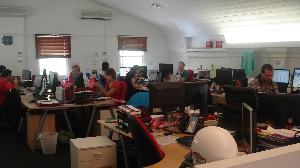 Open-plan office team working at shared desks, illustrating how company culture changes as a company grows beyond the Dunbar limit of about 150 people