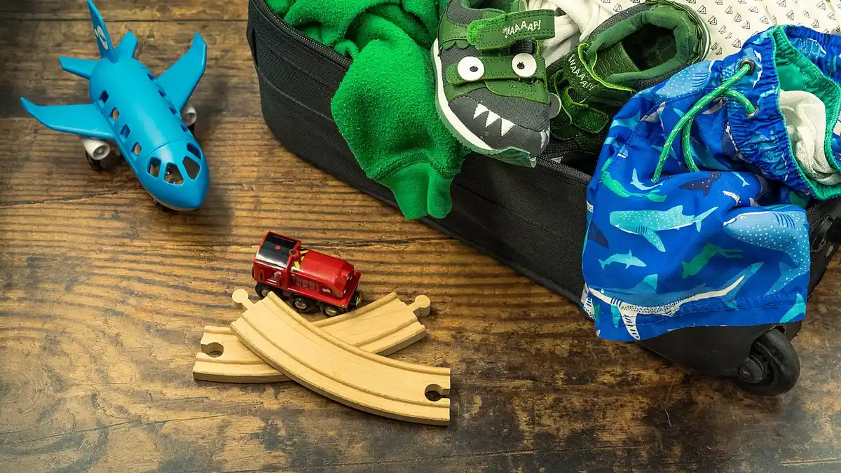 An open suitcase packed with folded clothes, ready for a trip with a portable scent tin tucked inside