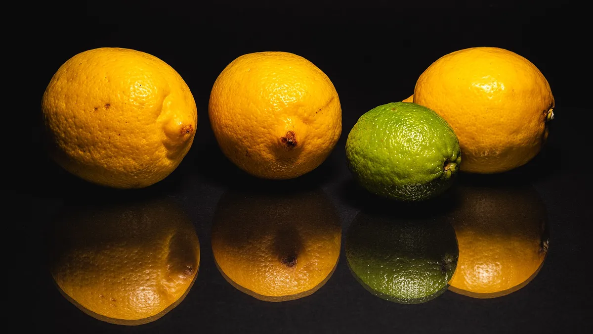 Fresh lemons and a lime on a dark background, the citrus fruits linked to vitamin C skincare