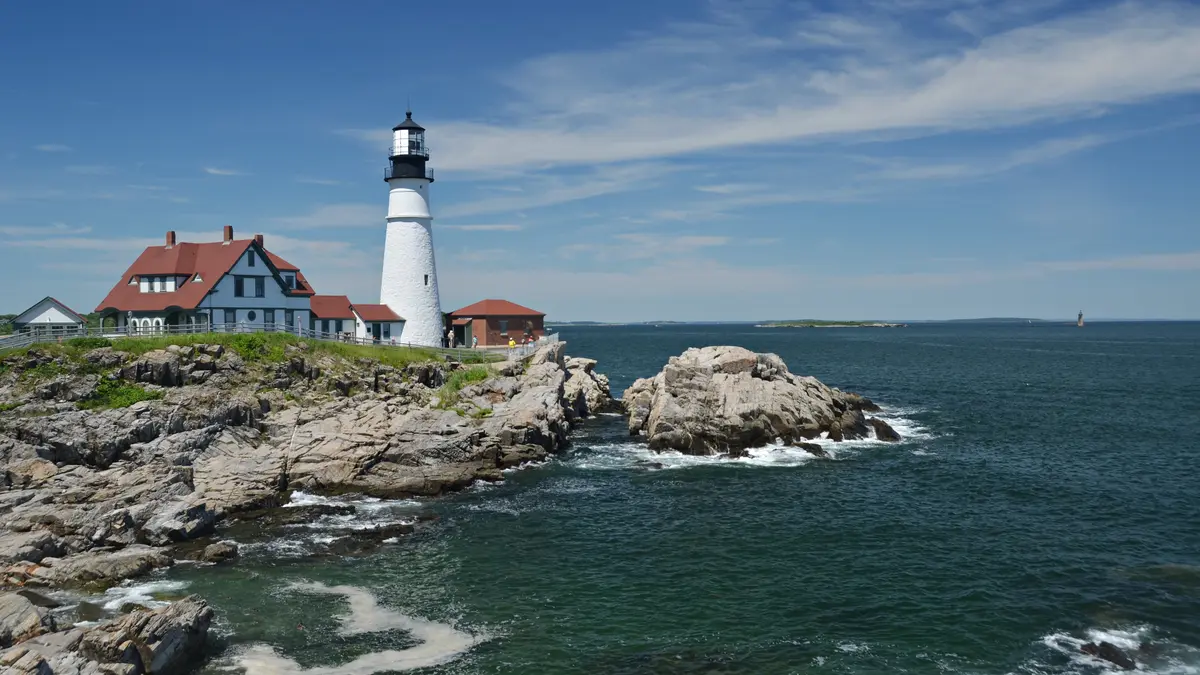 Portland Head Light lighthouse on a rocky Maine coast with waves in summer