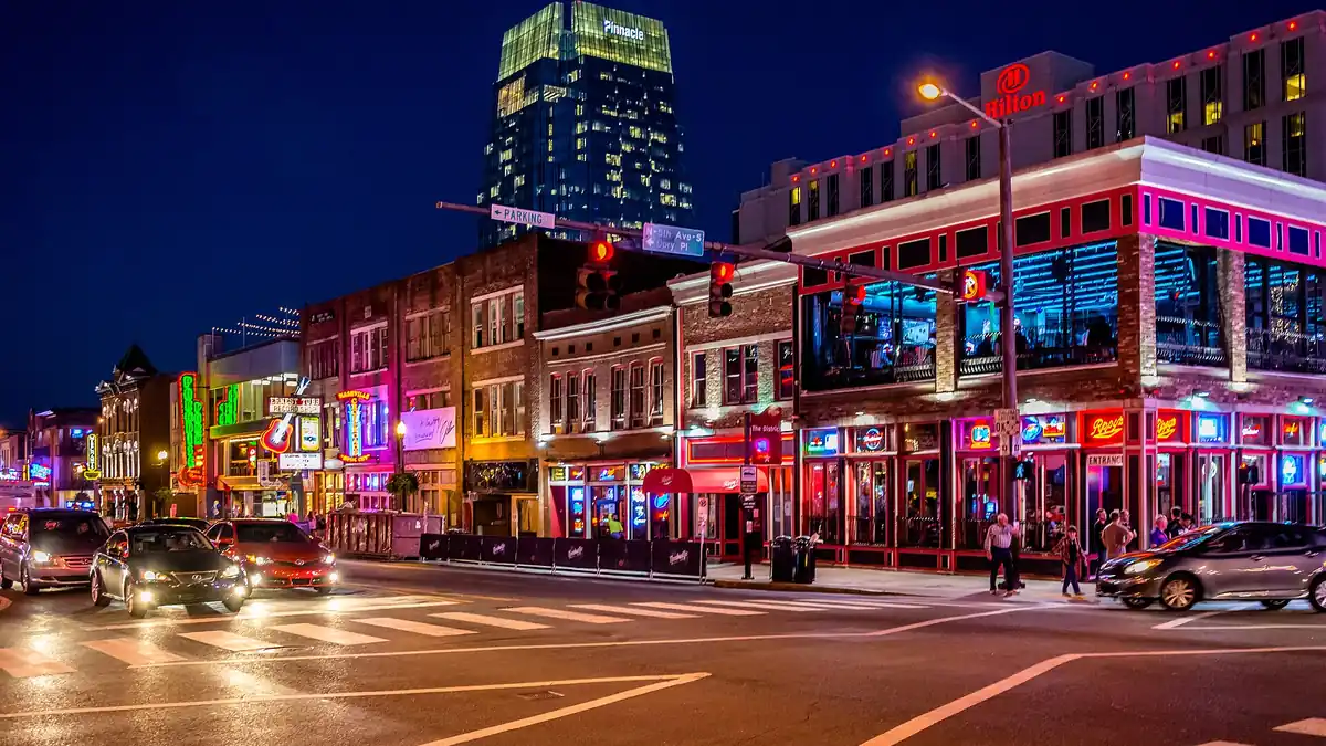 Lower Broadway in Nashville at night, with neon honky-tonk signs glowing above the street