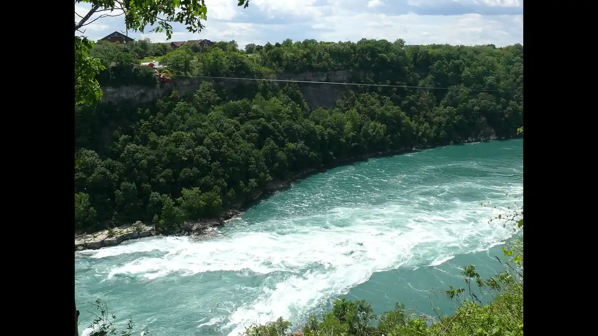 The Niagara Whirlpool swirling in the green Niagara Gorge below Niagara Falls, seen from the rim in autumn light