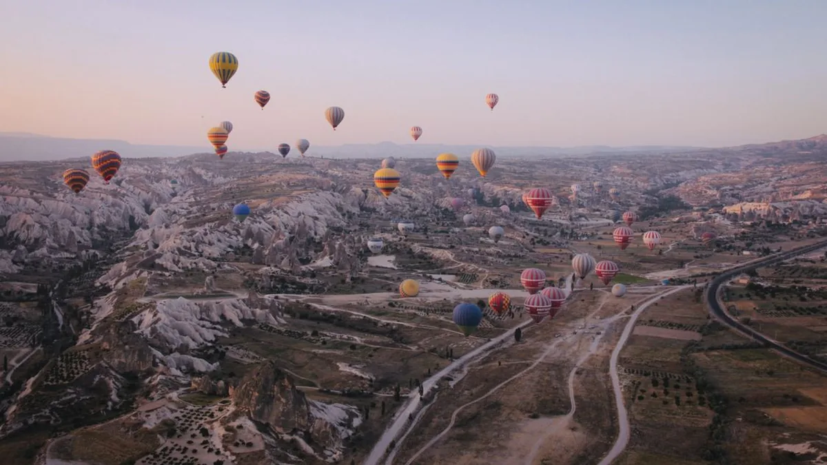Colourful hot air balloons floating over the rock formations of Cappadocia at sunrise