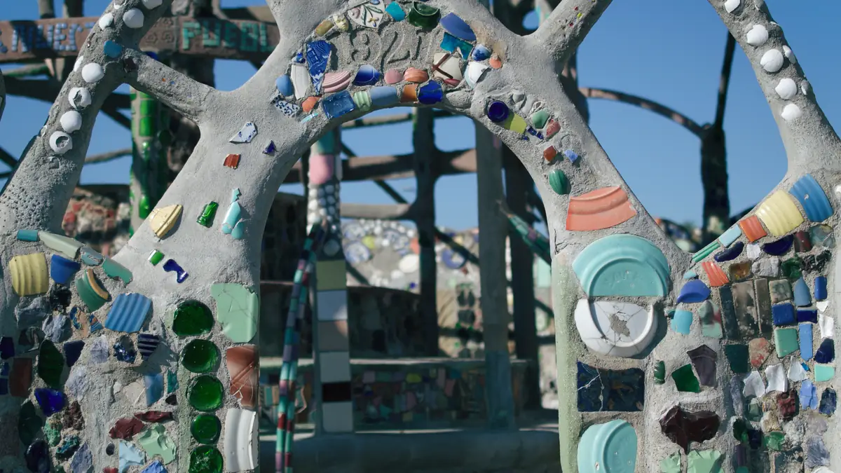 Watts Towers in Los Angeles, tall folk art towers covered in mosaic tiles, glass and shells against a blue sky