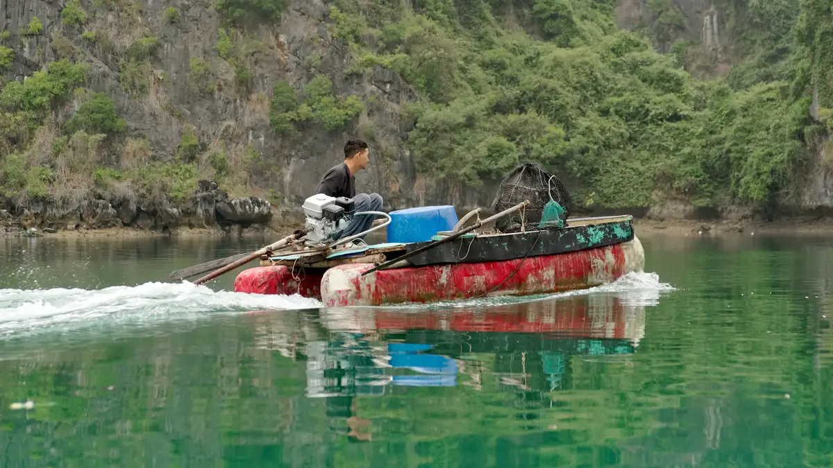 Traditional fishing boat on calm water near Cat Ba Island in Ha Long Bay, Vietnam, one of the cheapest places to visit in Asia