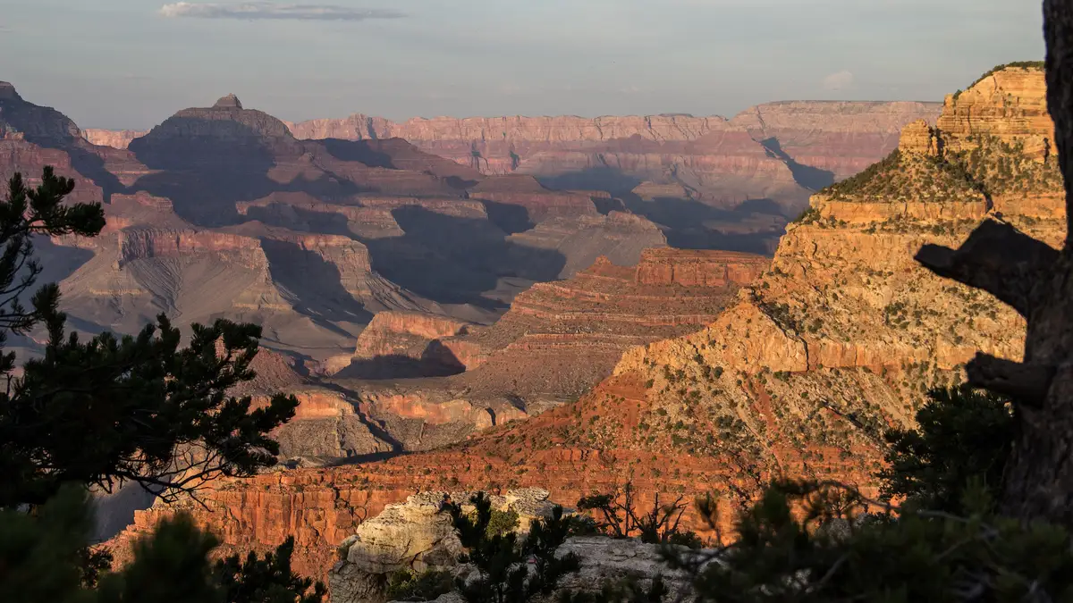 Sunset over the Grand Canyon South Rim near Tusayan, Arizona, with layered red rock walls fading into golden light